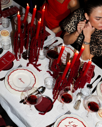 Chez Jules table styling by Imaginary Friends – red taper candles, scalloped plates, wine glasses and personalized dinner details in a bold red theme.