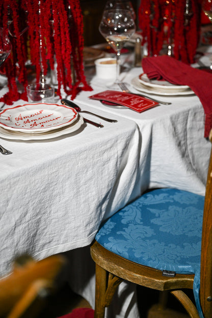 Chez Jules table styling – red candles, scalloped plates, personalized menu cards and a contrasting blue cushioned chair by Imaginary Friends.