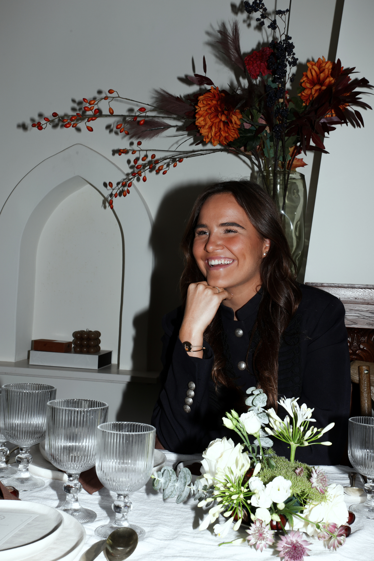 Pien de Pont, co-founder of Imaginary Friends, seated at a styled dinner table with glassware and white floral arrangements.