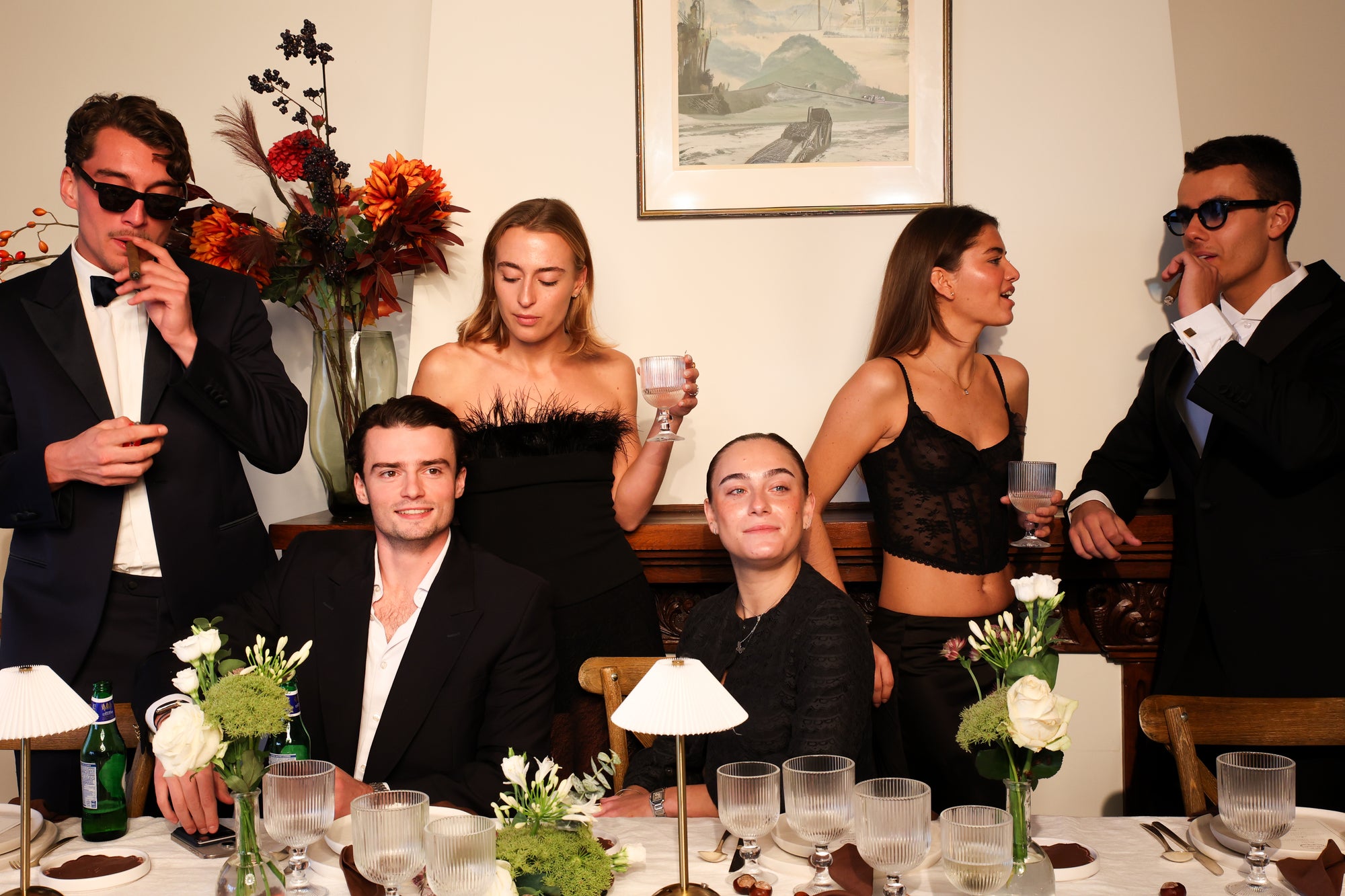 Group of guests dressed in formal eveningwear around an elegant dinner table styled by Imaginary Friends, with florals, glassware, and warm lighting.